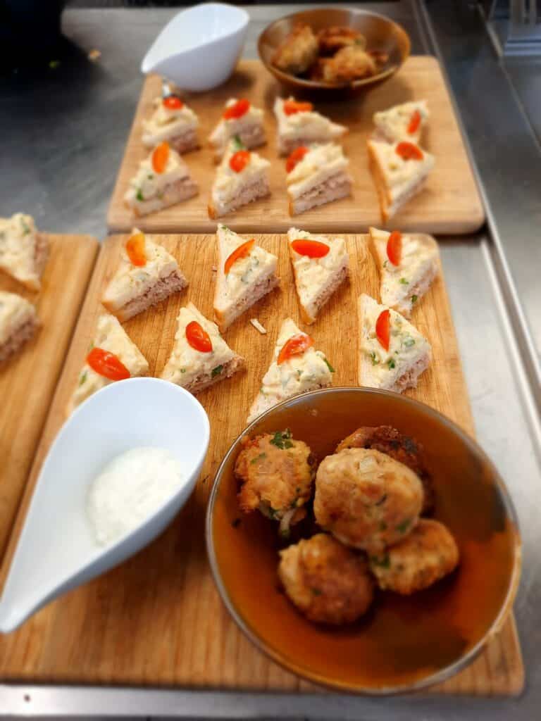 Tuna sandwiches and tuna fritters served with yogurt sauce on a wooden tray
